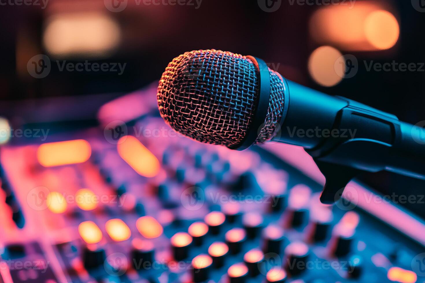 A microphone is on a sound board with a red and purple background. The microphone is black and silver photo
