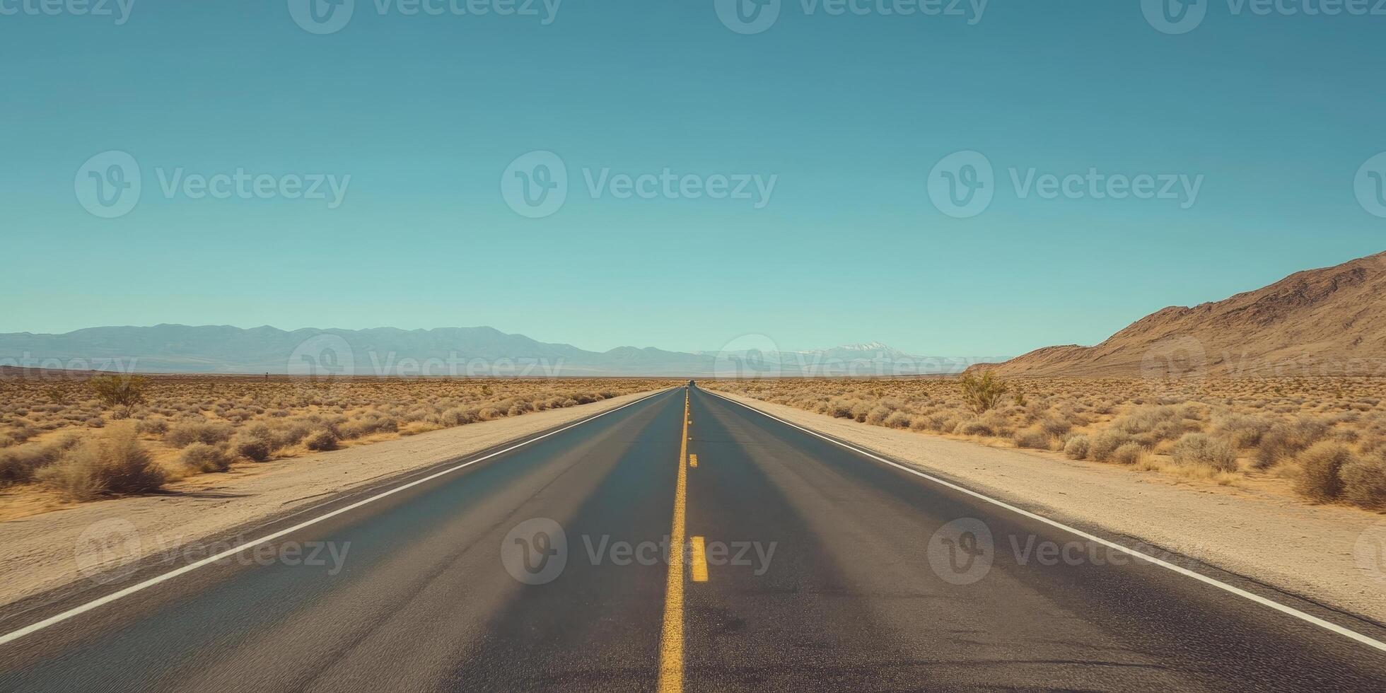 Endless Desert Highway Under Clear Blue Sky with Distant Mountains in the Horizon photo