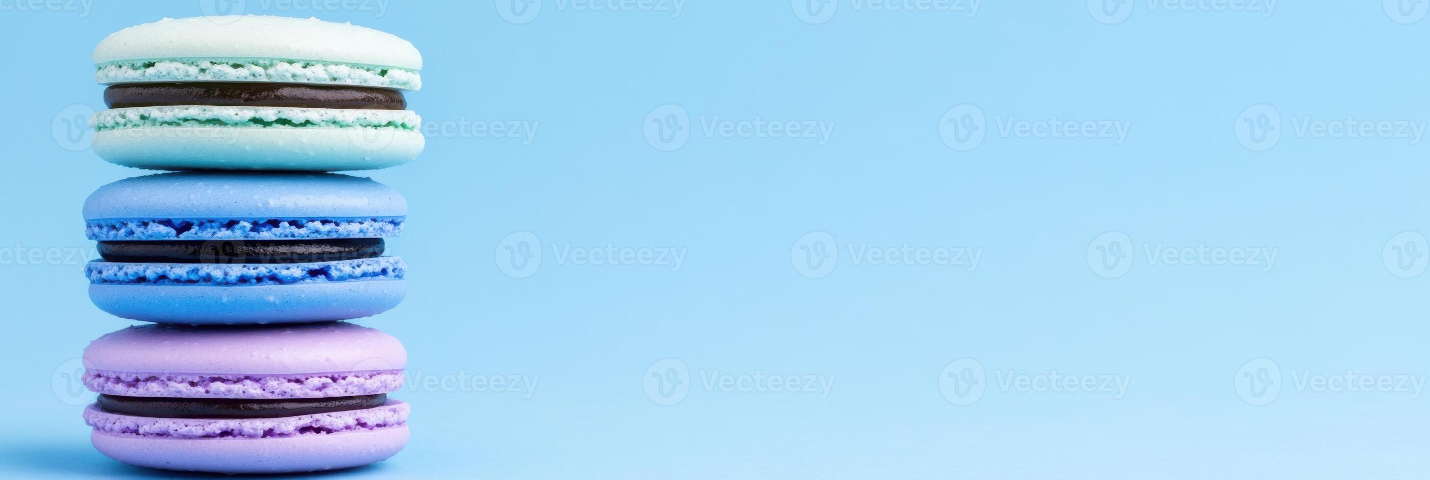 Stack of colorful macarons in shades of blue and lavender on a pastel backdrop photo