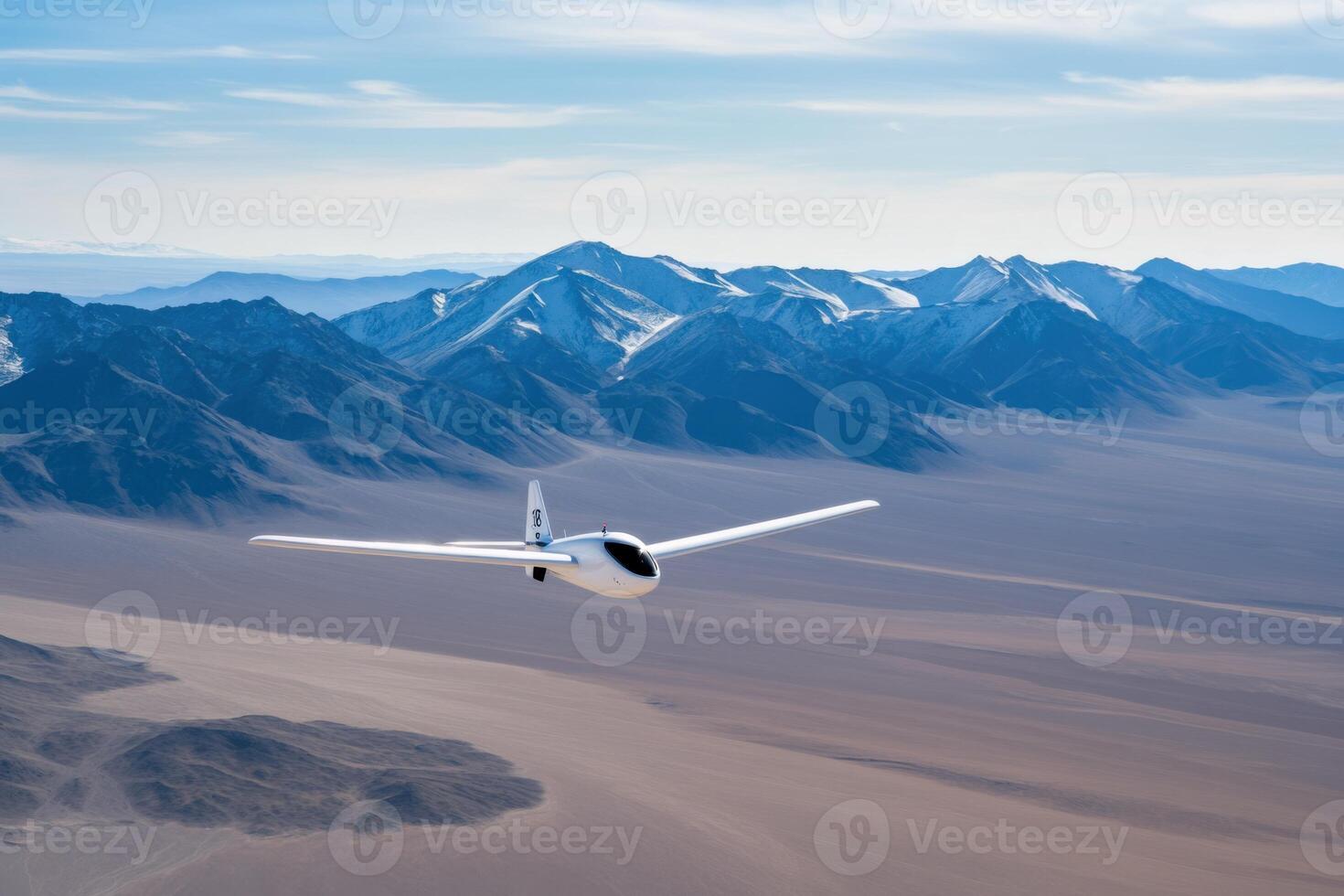 Drone captures stunning aerial views over a vast gray-brown desert landscape with majestic black mountains in the backdrop during a bright day photo