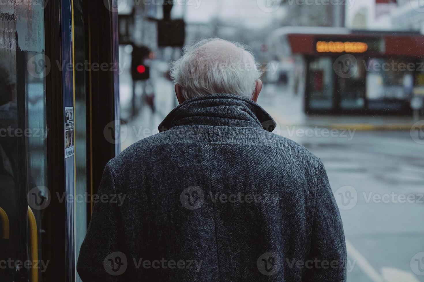 Elderly man standing by the bus stop on a cold winter day with frosted city surroundings photo