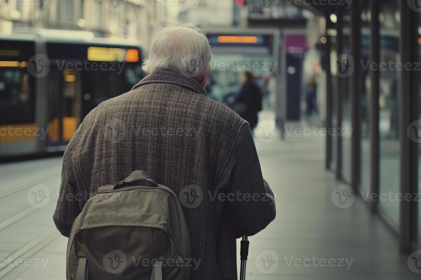 Elderly man using a walking cane approaching bus on a city street during autumn photo