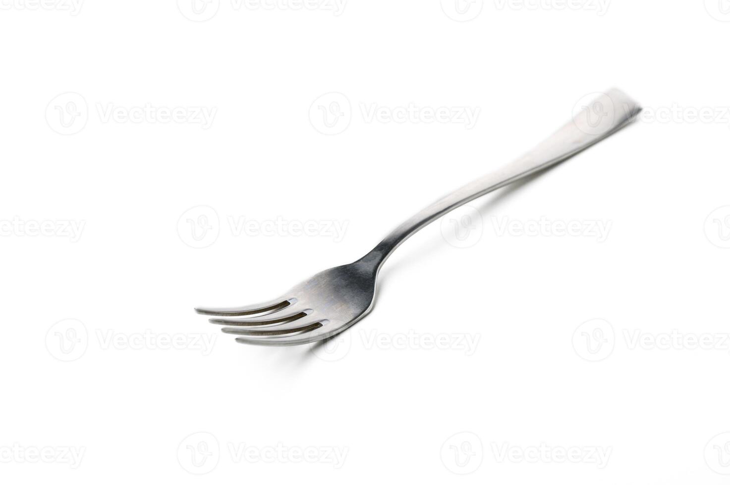 Unique silver fork with elongated tines resting on a plain white surface at midday photo