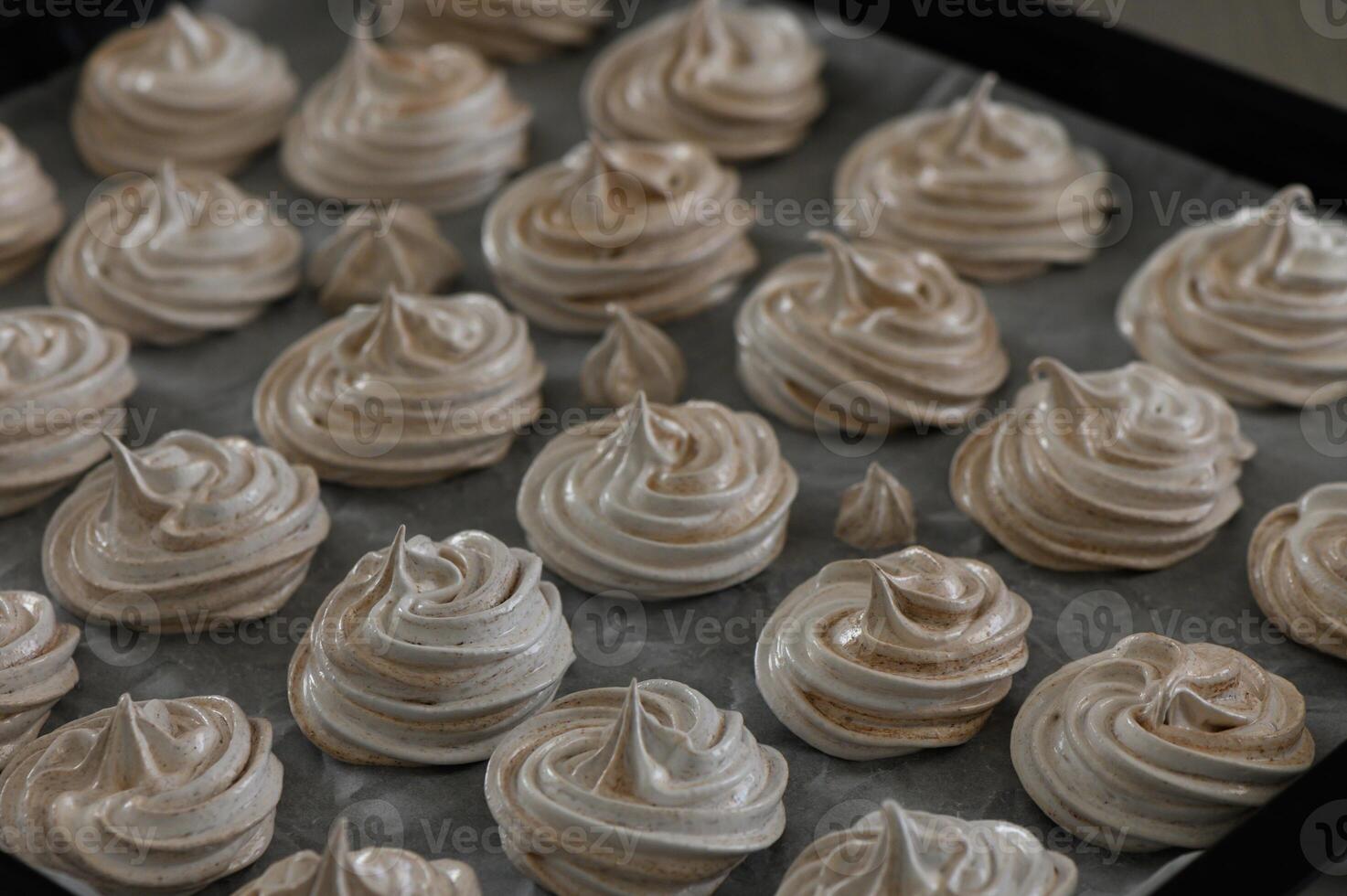 Delicate meringue cookies arranged artistically on a baking tray before baking in a cozy kitchen photo