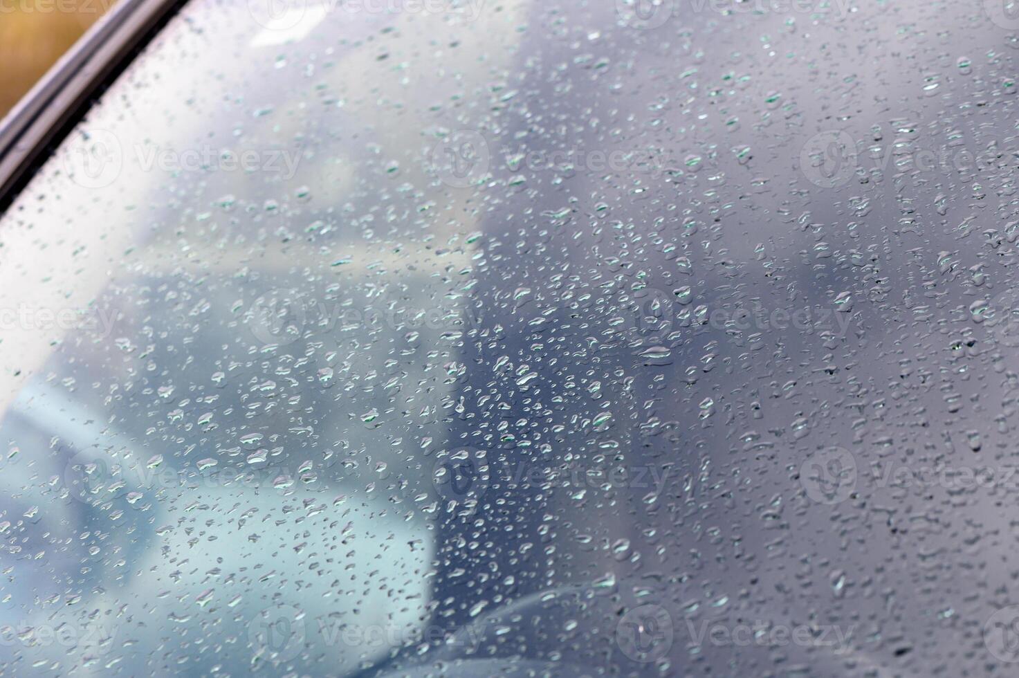 Raindrops gently collect on a car window during a cloudy afternoon in the city photo