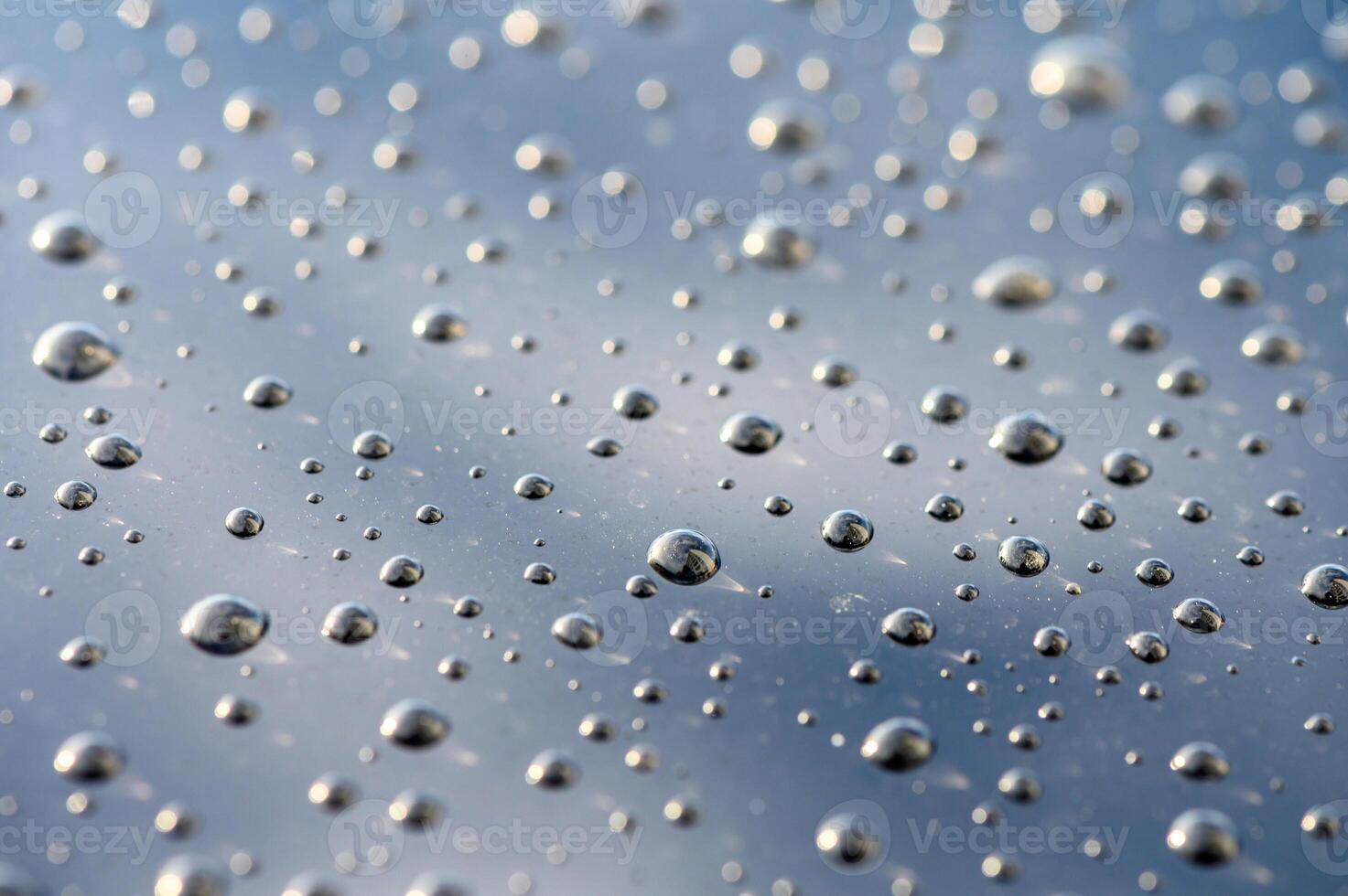 Raindrops dance on a reflective surface under a cloudy sky during a tranquil moment of nature photo