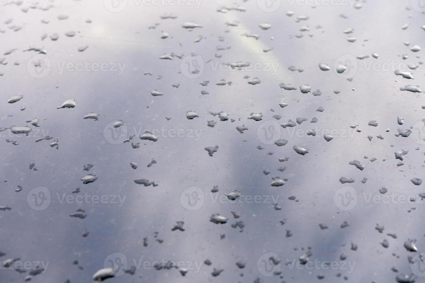 Raindrops dance on a reflective surface during a quiet afternoon in an urban setting photo