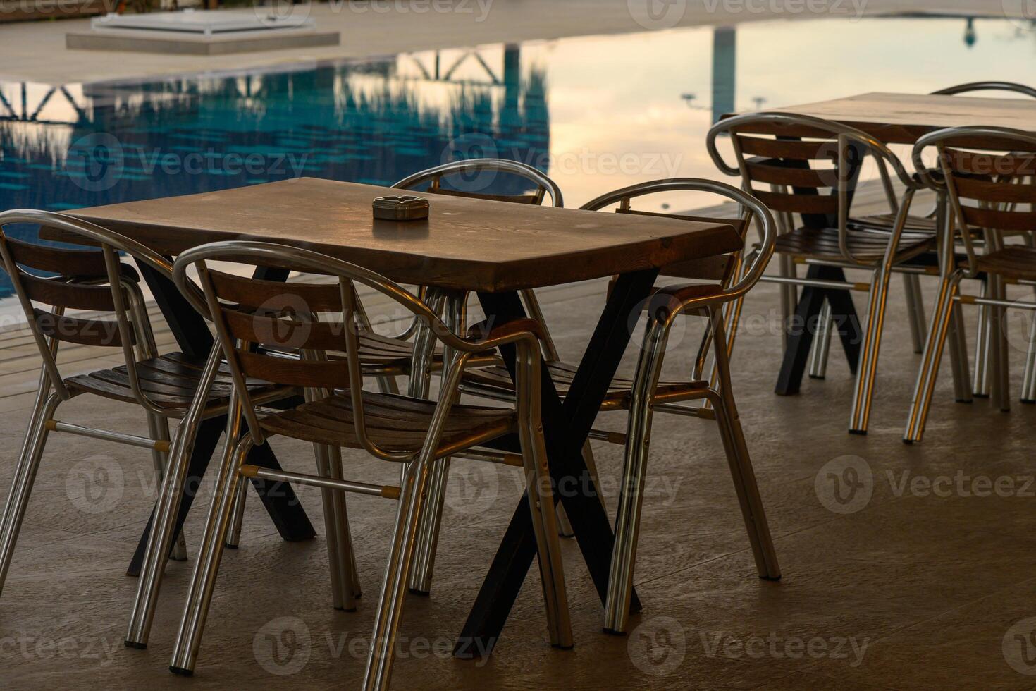 Charming outdoor dining setup by a tranquil swimming pool in the evening glow photo