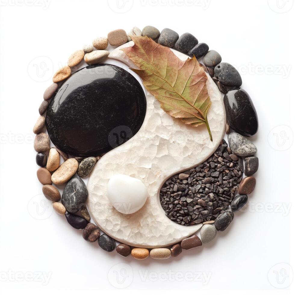 Decorative yin yang design created from natural stones and a leaf displayed on a white background photo