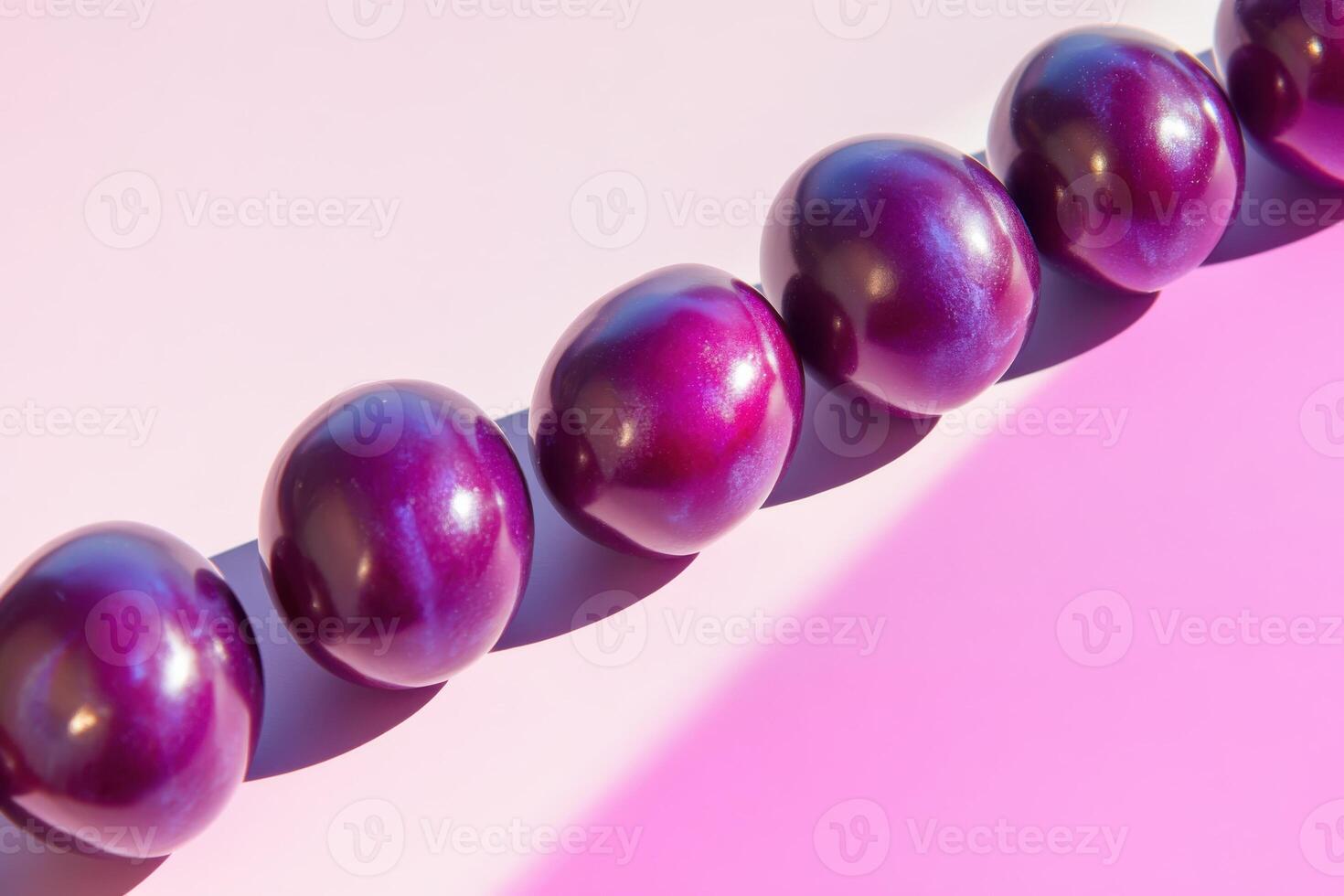 Row of shiny purple spheres on pink background with gradient light effects photo