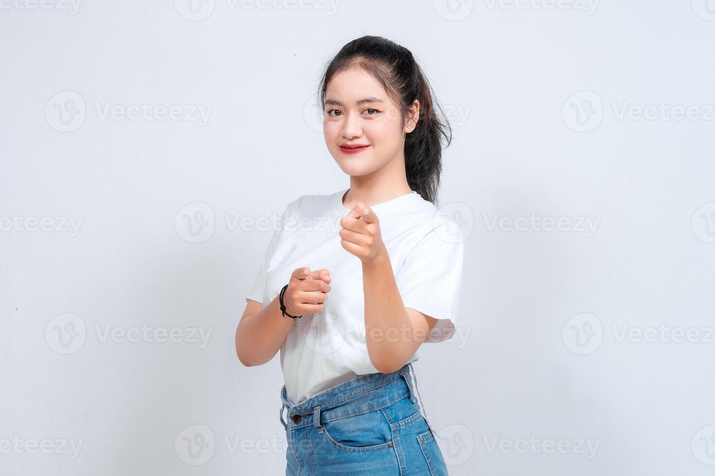 Young pretty woman smiling joyfully and looking happy pointing forward, Looking at Camera, make choosing you gesture against white background photo
