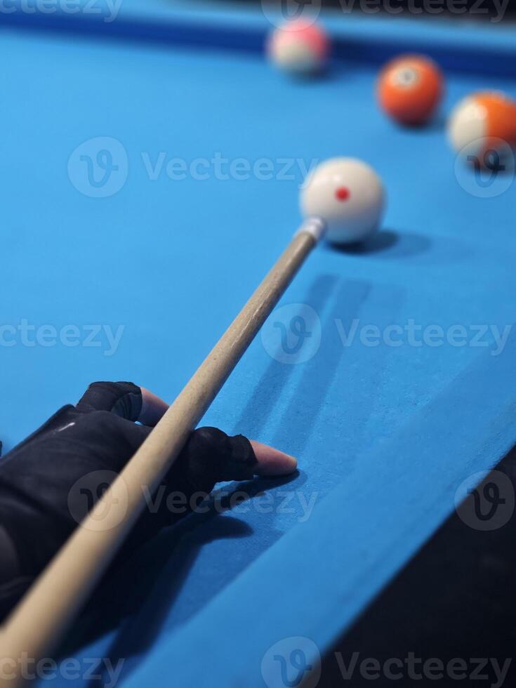 Billiard cue in hand of male player standing by pool table and concentrating before hitting white ball during game. photo