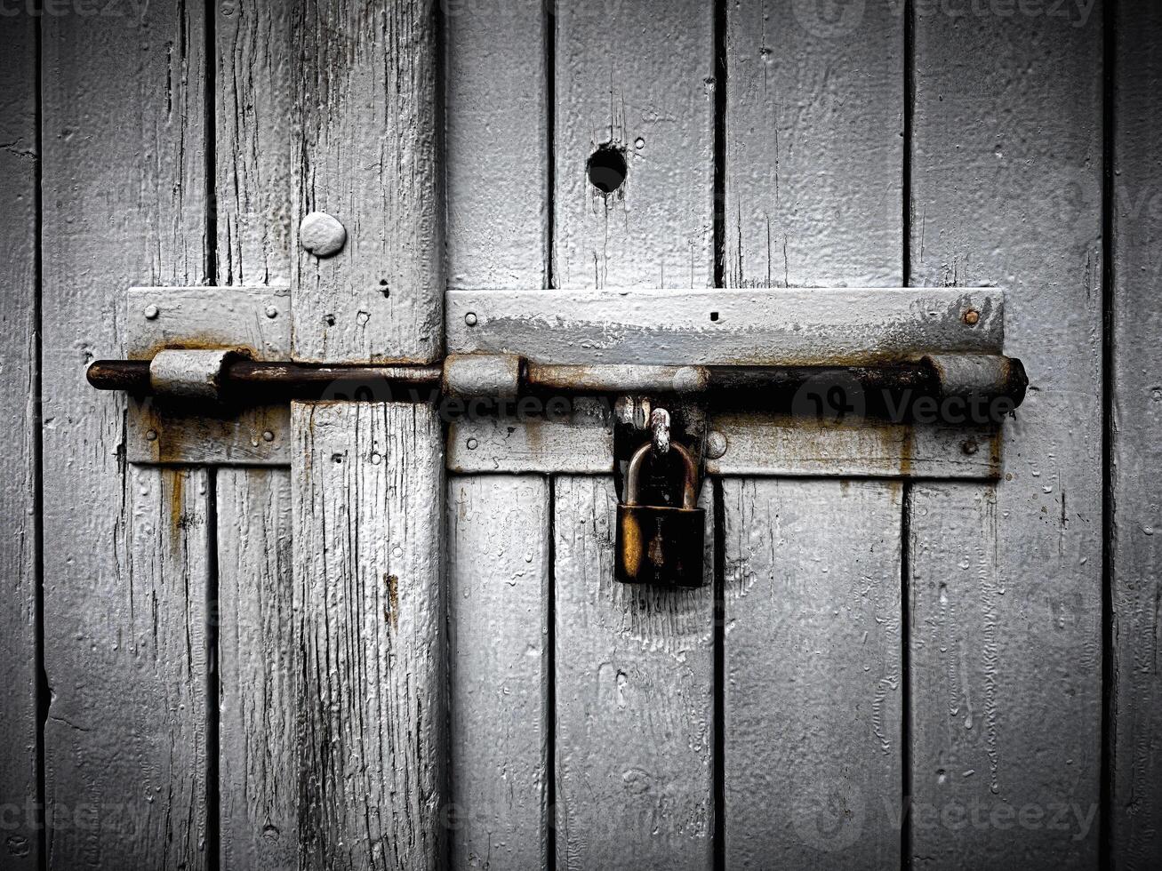 Old wooden door locked with rusty padlock, background texture. photo