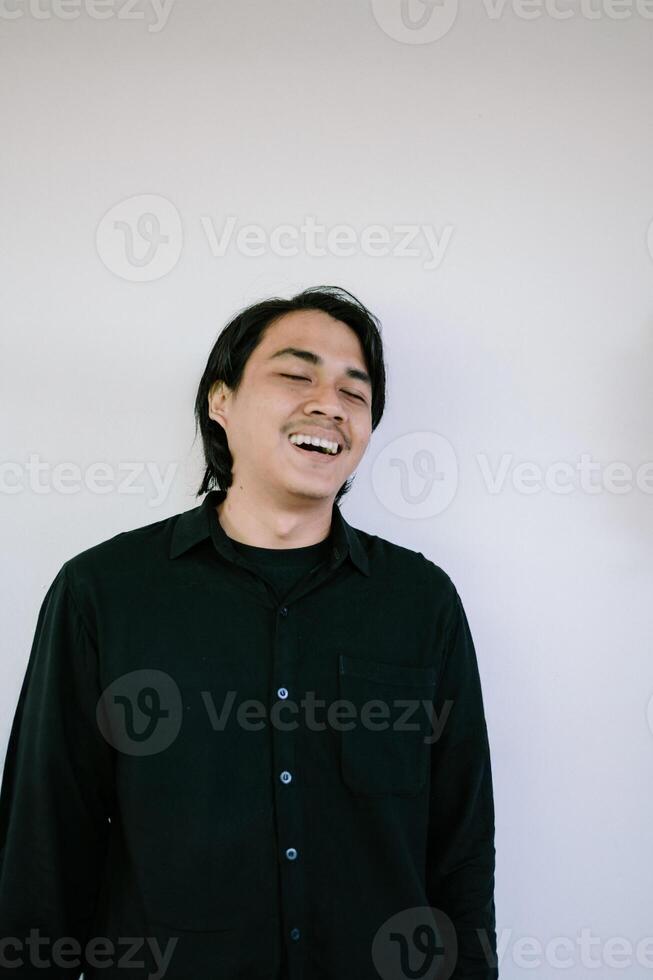 Smiling man in a black shirt laughing against a plain white background, photo