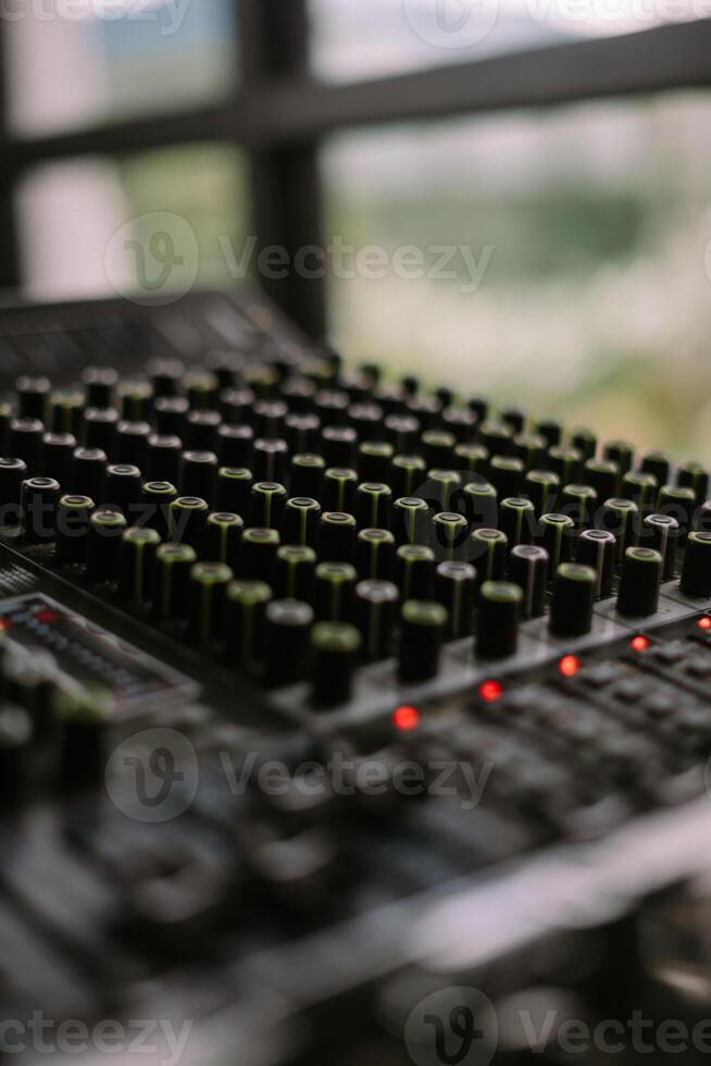 Close-up view of a sound mixer with numerous knobs and faders, ideal for music production photo