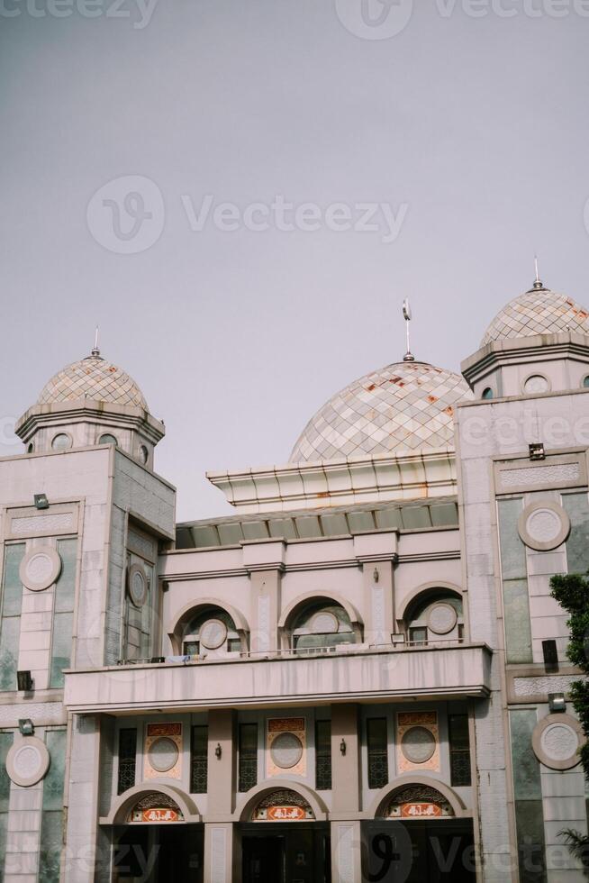 The serene domes of a mosque rise against a soft sky photo