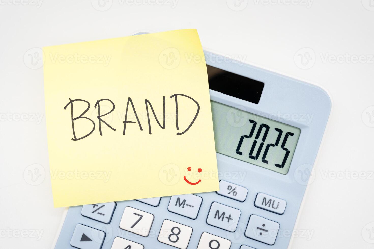 BRAND text on sticky note with light blue Calculator. Build your Brand in 2025. Brand building, success, business. Calculator and forecast for finances in 2025. photo