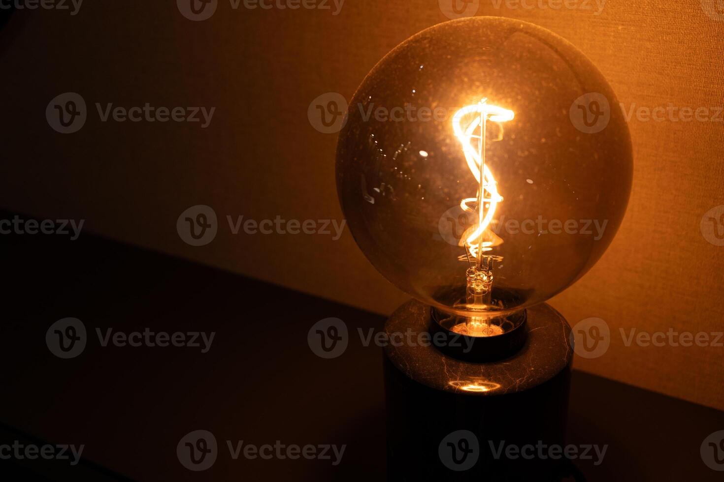 Vintage Light Bulb Glow. Warm Light Bulb in Dark. Illuminated Light Bulb. Retro Lighting Ambiance. Copy space. photo