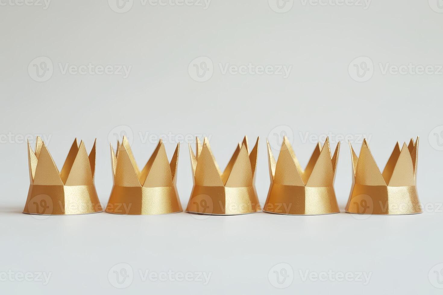 Six Golden Paper Crowns in a Row on a Minimalist White Background photo
