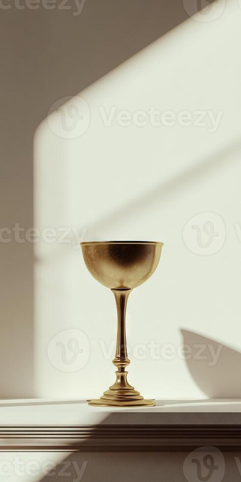 A gold cup sits on a shelf in front of a window photo