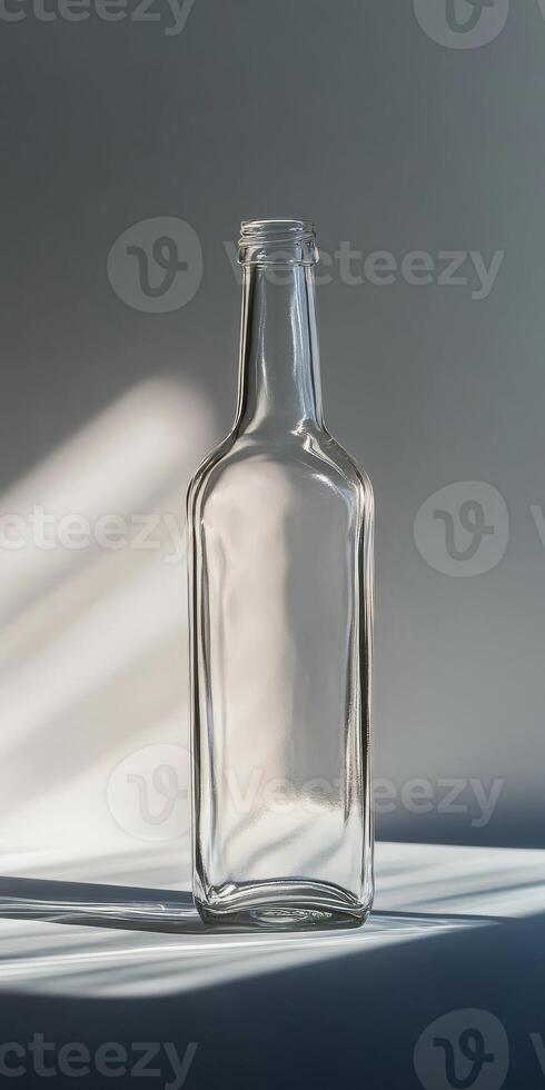 Minimalist Glass Bottle with Sunlit Shadows on a Neutral Background photo