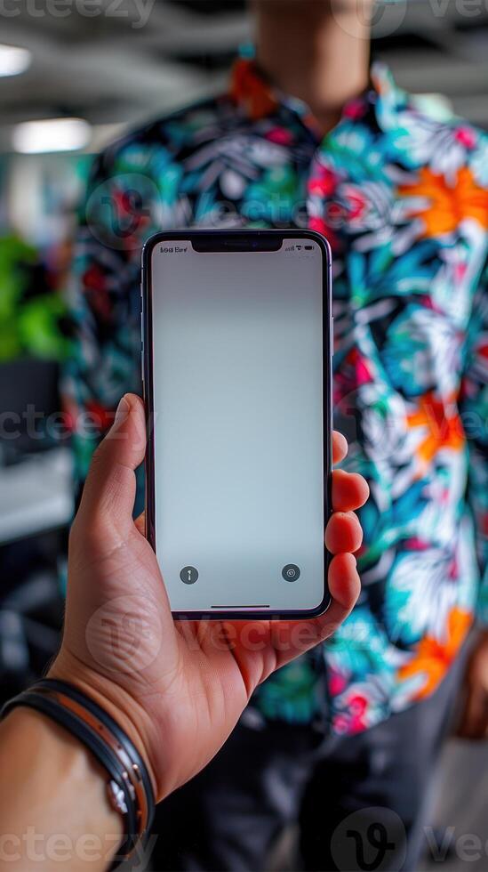A man holds up a smartphone with a blank screen against a colorful patterned background photo