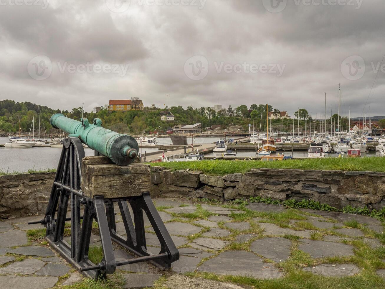 A cannon on a stone wall overlooking a harbor photo