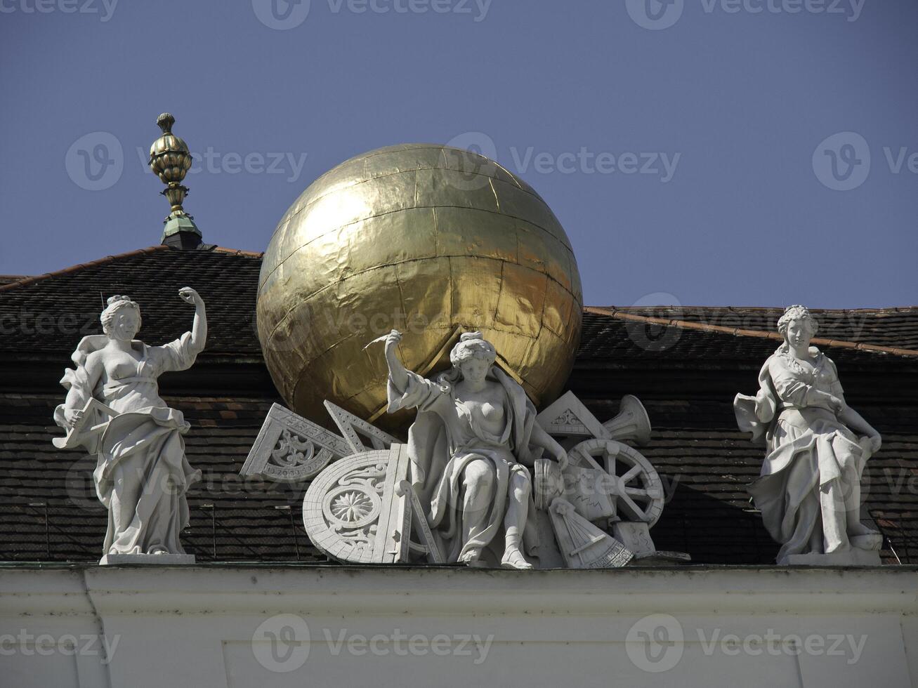 A statue of a globe on a building with statues of people photo