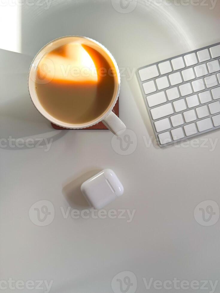 Cup of coffee with a heart-shaped reflection for Valentines day, placed on a clean white desk. Soft lighting and minimalistic workspace. Love and technologies concept. photo