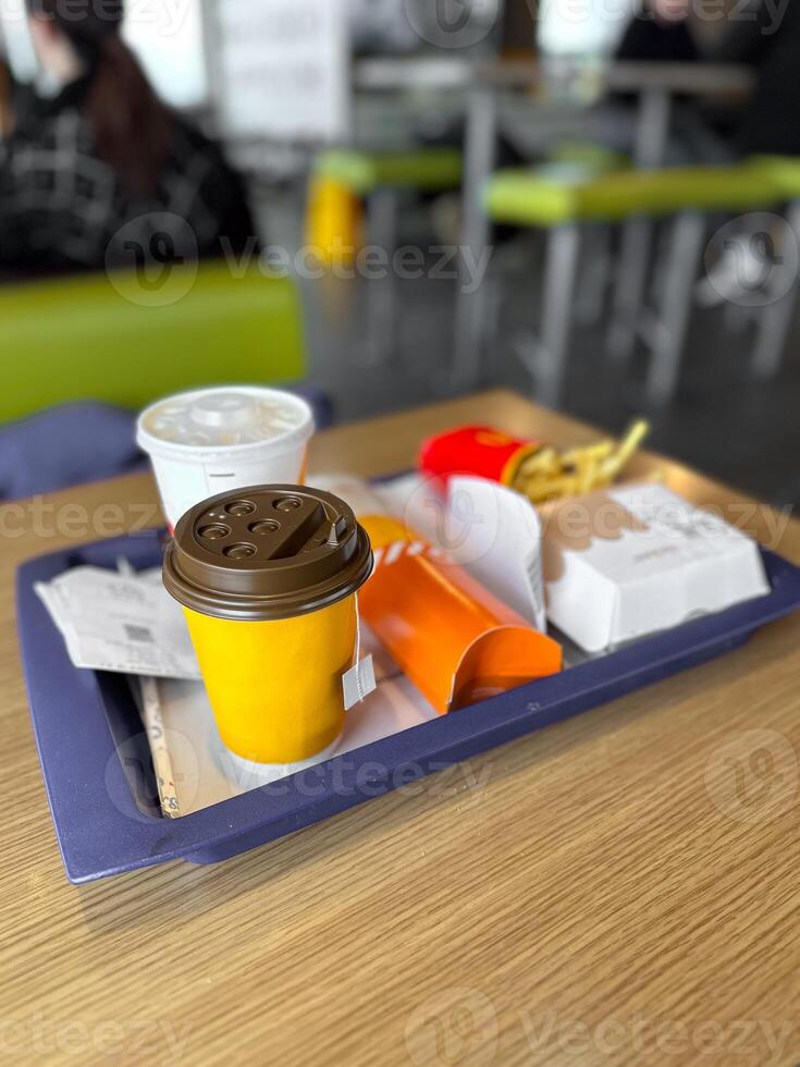 Fast food tray featuring a cup of coffee and soft drink. Snacks including fries and burgers. Lunch time and quick dining concept photo