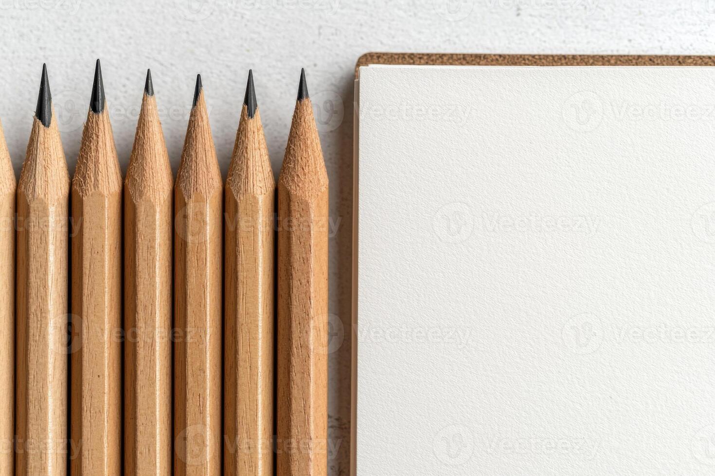 Close up of sharpened pencils next to a blank notebook photo
