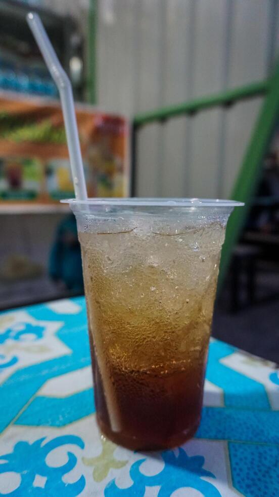 Iced Tea in Plastic Cup with Straw on Colorful Table photo