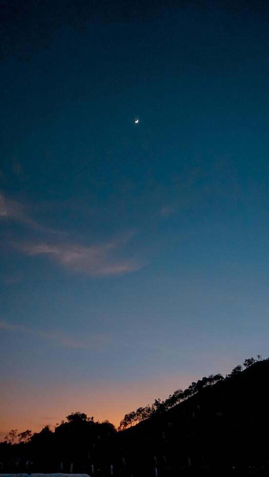 Crescent Moon Over Silhouetted Hills at Twilight photo