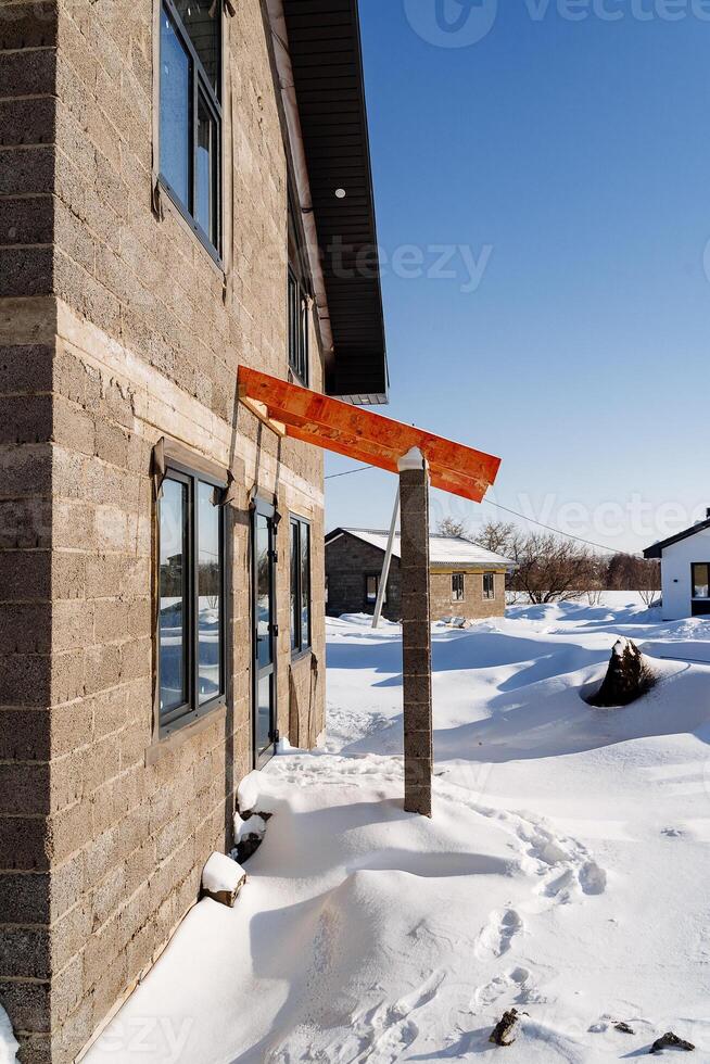 A house with a red awning on the side, against a snowy backdrop photo
