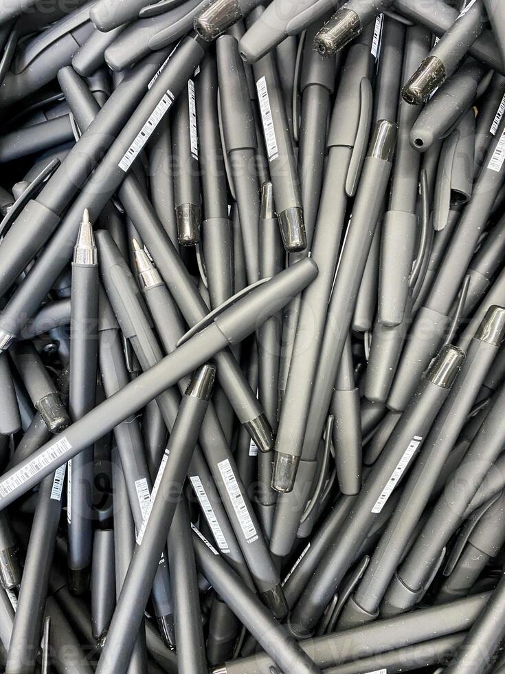 A sizable stack of black pens can be seen, each with a sleek design and smooth finish, perfect for writing or artistic endeavors, showcasing an array of patterns or styles photo
