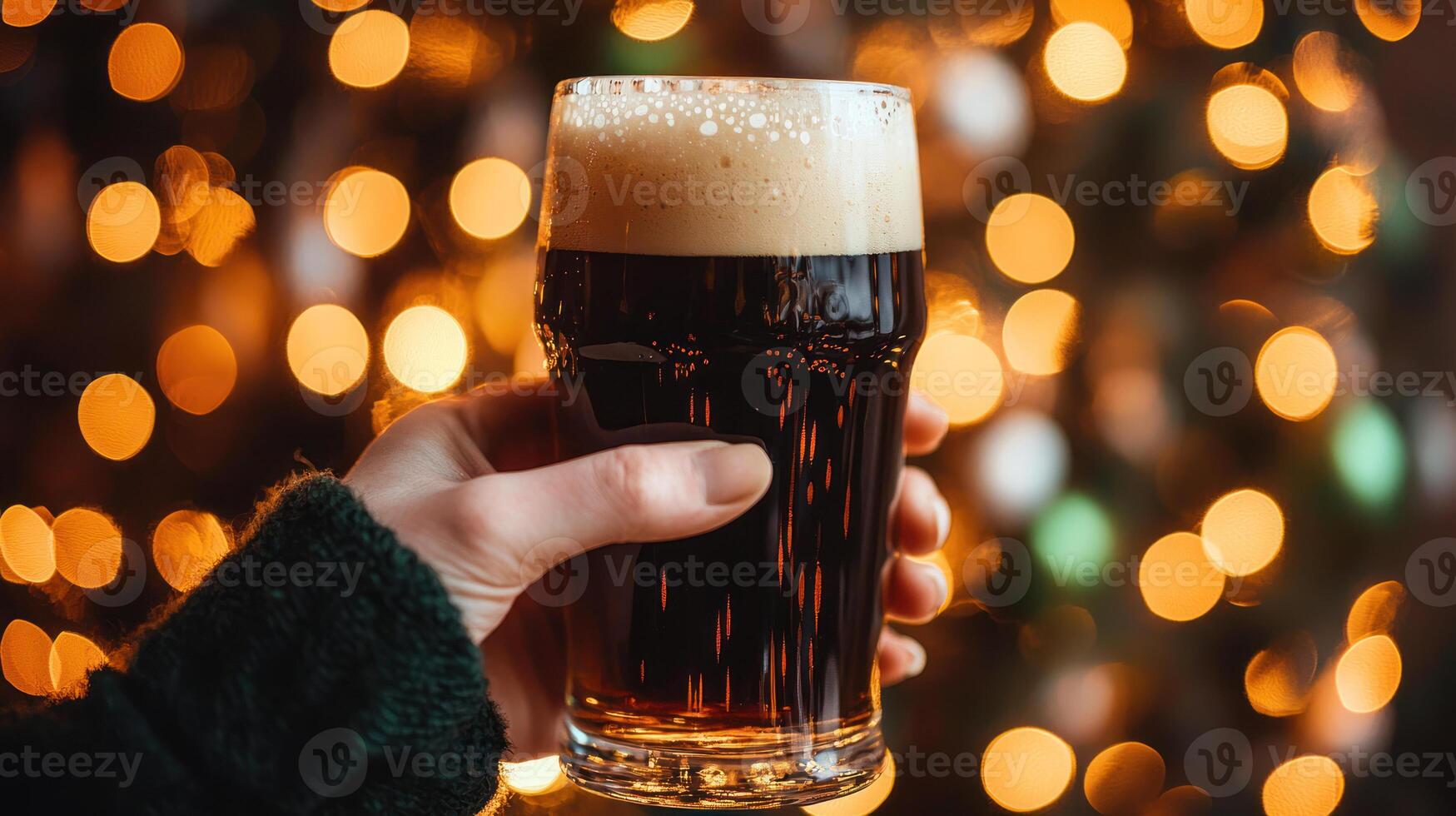 hand holding pint of stout with frothy top, festive lights in background photo
