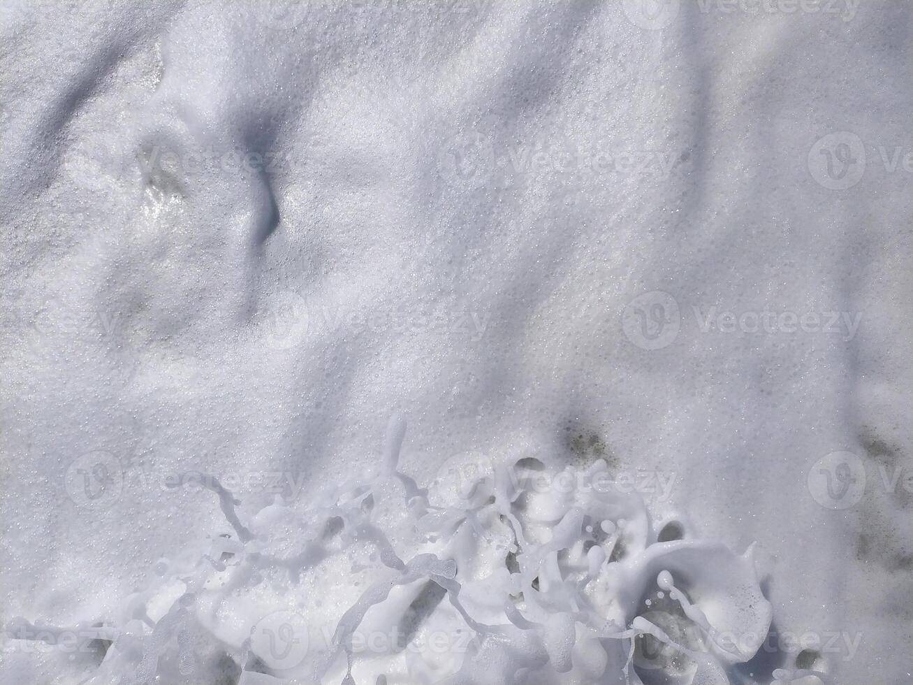 Gentle waves rolling onto beach at sunrise, creating bubbles and a shimmering surface photo