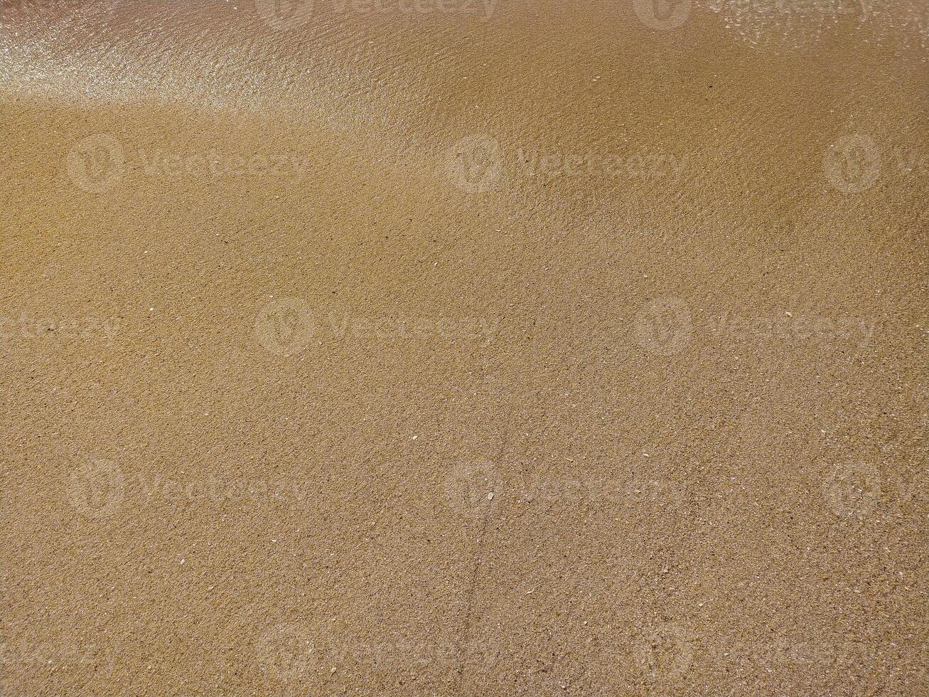 Fine golden sand covering a beach during a sunny day skies, creating a serene and tranquil atmosphere for relaxation photo