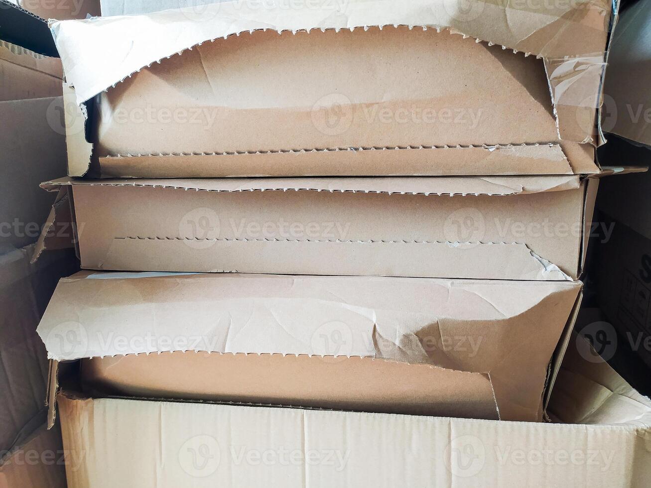 Stack of damaged cardboard boxes, showing wear and tear. Ideal for illustrating shipping, moving, recycling, or the concept of disposal. The image has a rustic, realistic aesthetic. photo