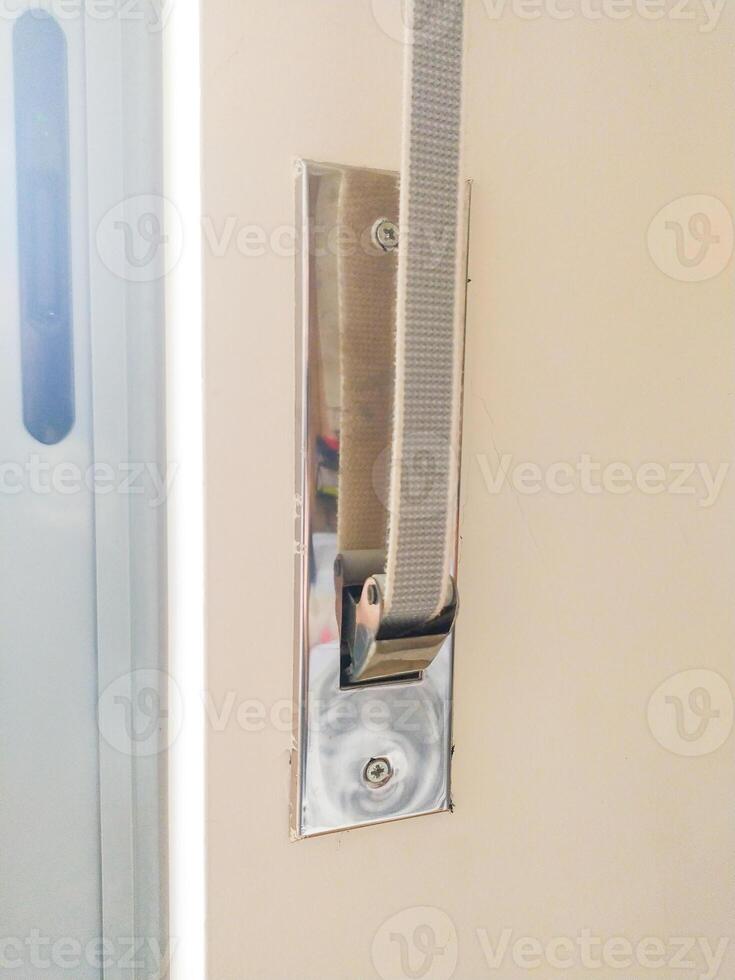 Closeup of a light grey fabric strap secured to a polished chrome wall mount. Ideal for websites, blogs, or DIY projects showcasing home improvement, interior design, or industrial applications. photo