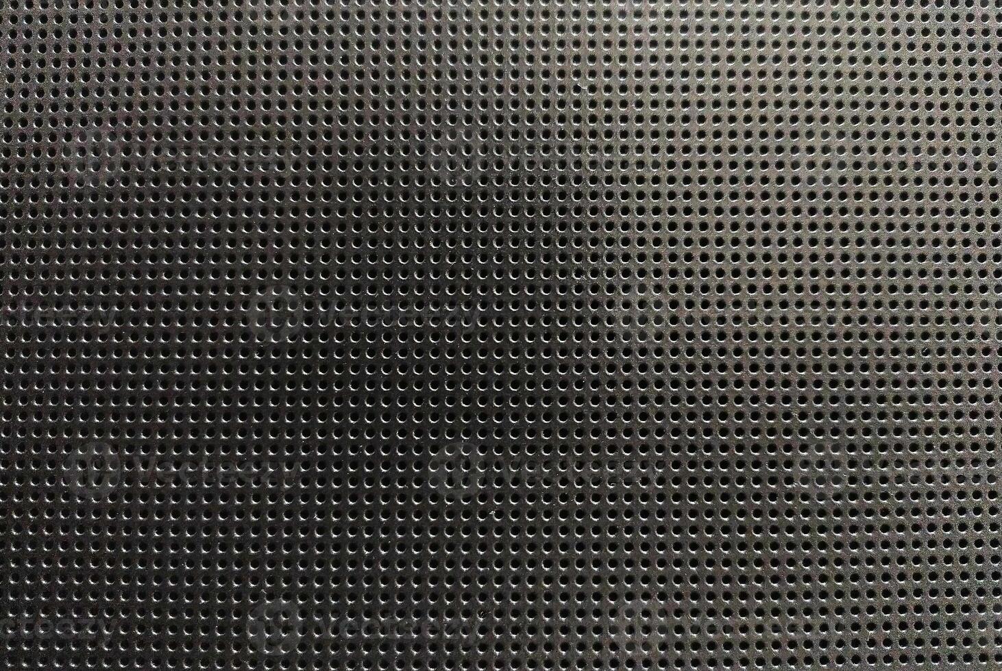 Highresolution image of a dark gray perforated metal sheet. Uniformly spaced round holes create a textured background ideal for industrial, tech, or abstract design projects. photo