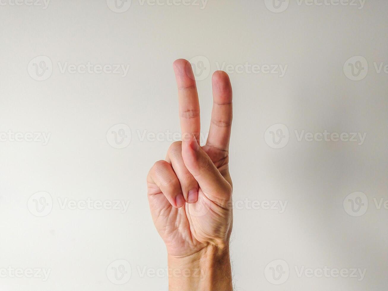 Closeup of a hand displaying the peace sign against a neutral background. Perfect for concepts of peace, unity, victory, or number two. Versatile image for websites, presentations, and social media. photo