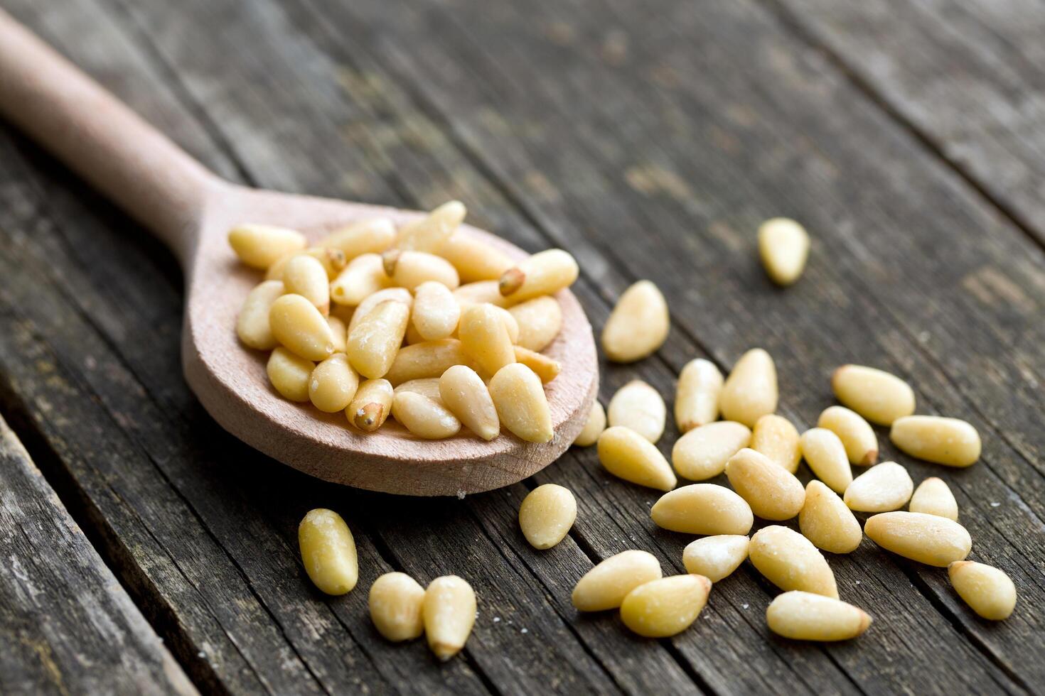 A spoon full of pine nuts on a wooden table photo