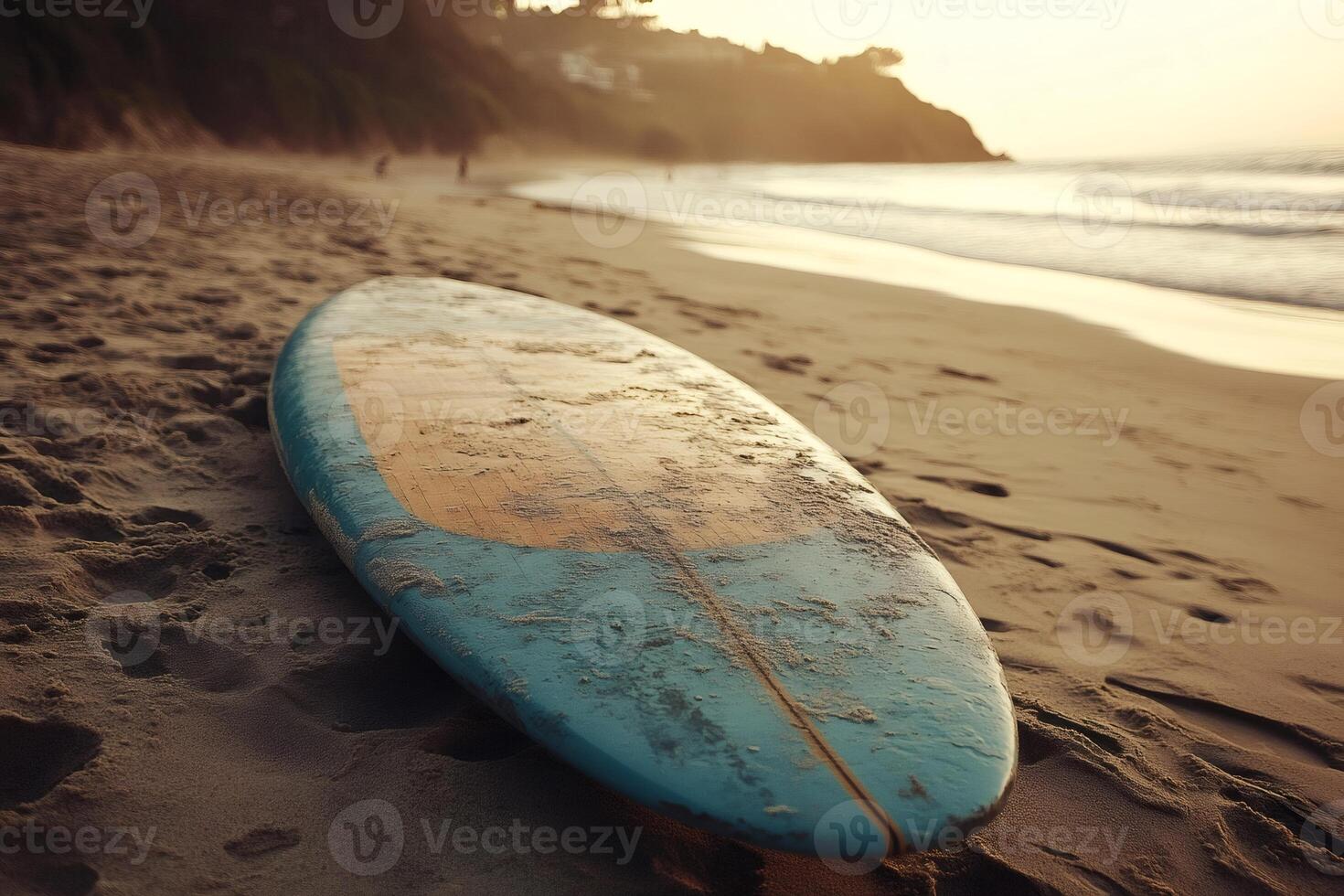 Surfboard lying on the beach at sunset with people walking in the background photo