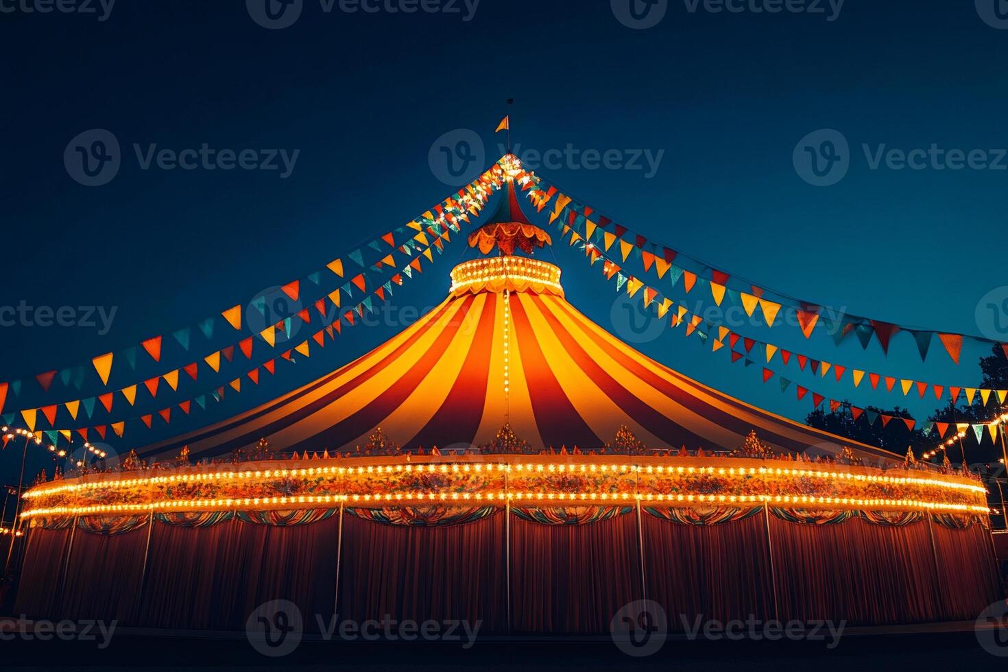 Large circus tent illuminated at night with colorful flags. photo