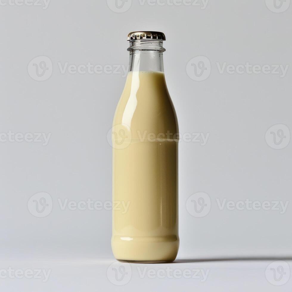A glass bottle filled with a creamy white liquid stands against a white background photo