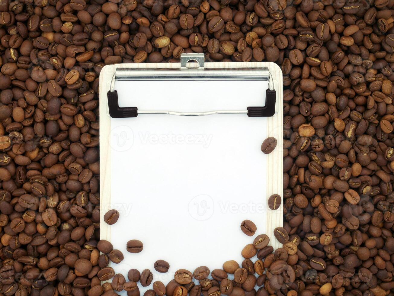 Board on coffee beans texture background. Paper for notes. Top view. photo