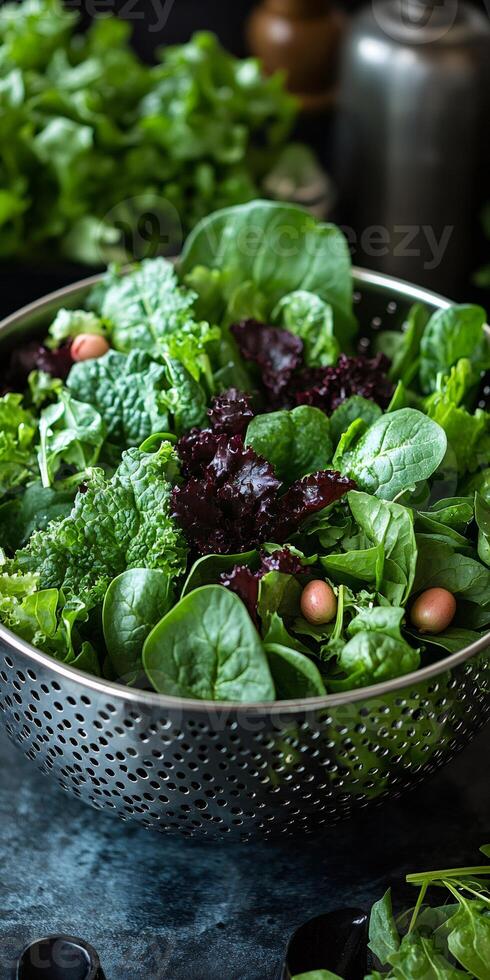 Fresh green salad leaves mix in metal colander getting washed and prepared for healthy meal photo