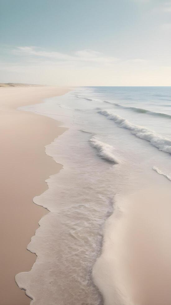 A vertical landscape of a calm seaside, with delicate waves washing over the sand, soft pastel tones, and a wide sky for adding text. photo