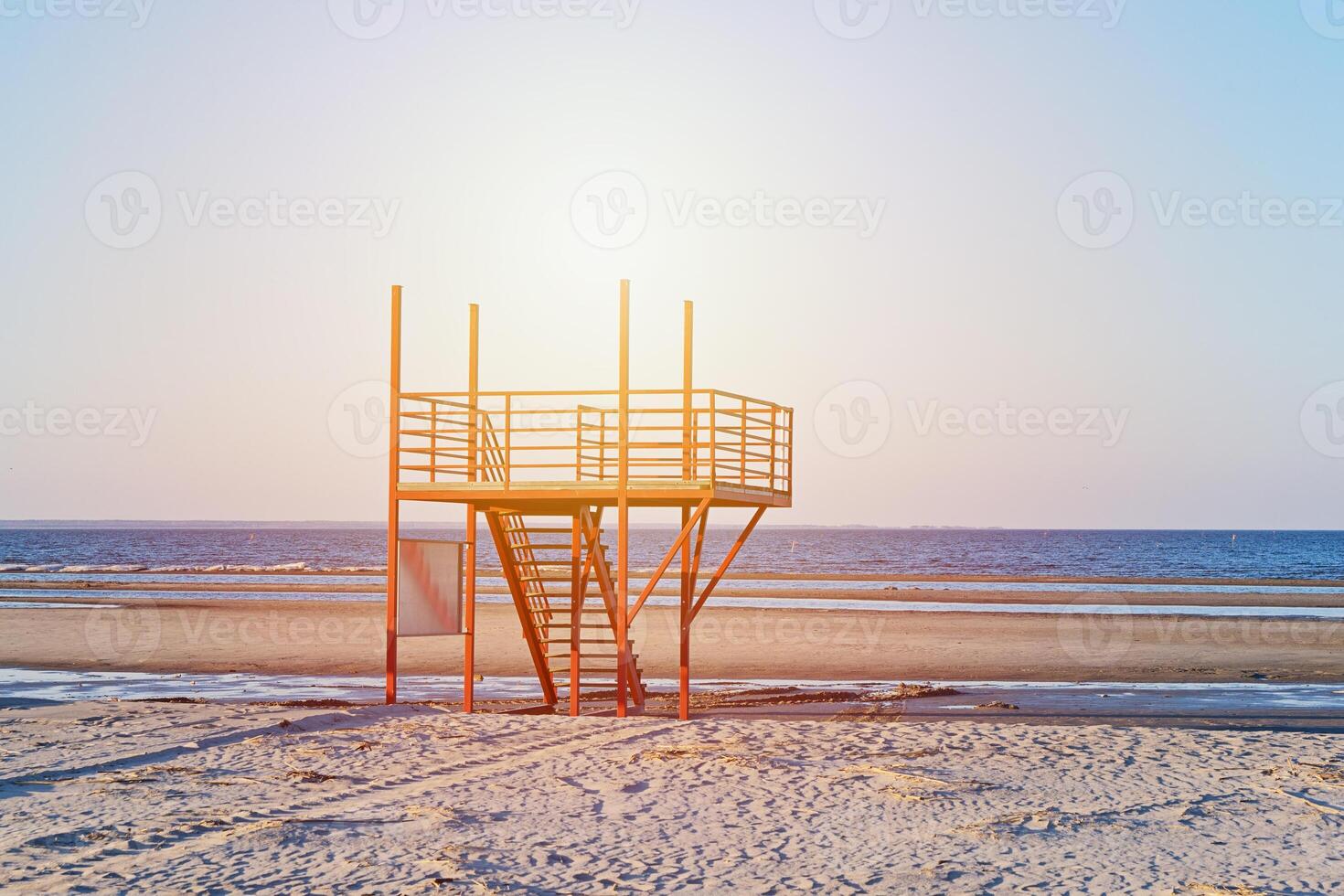 View of sunset sandy beach with red empty modern lifeguard tower photo